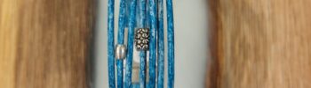 Bracelet en cuir bleu lagon, composé de 7 cordons de cuir de 2 mm et orné de perles en acier inoxydable. Son fermoir magnétique assure confort et sécurité. Un accessoire élégant et moderne, parfait pour ajouter une touche colorée et sophistiquée à votre look.